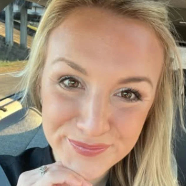 Woman with blonde hair and a black top sitting inside a vehicle.